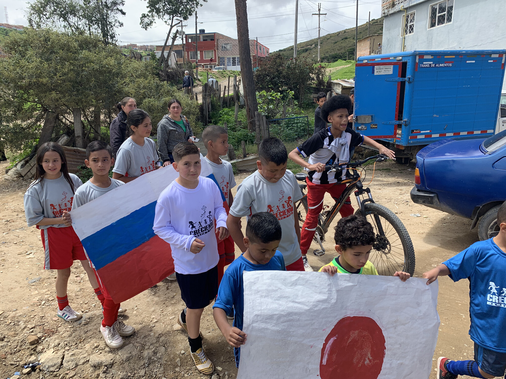 A group of children in Colombia. Two are holding makeshift country flags.