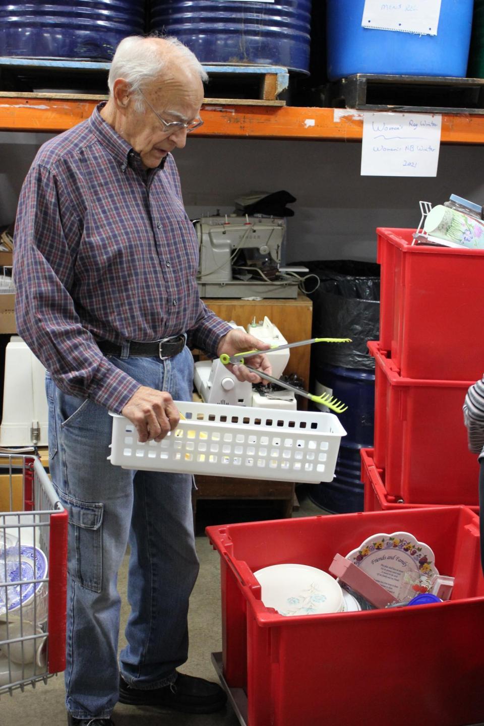 An older man sorts through items in the backroom of a thrift shop
