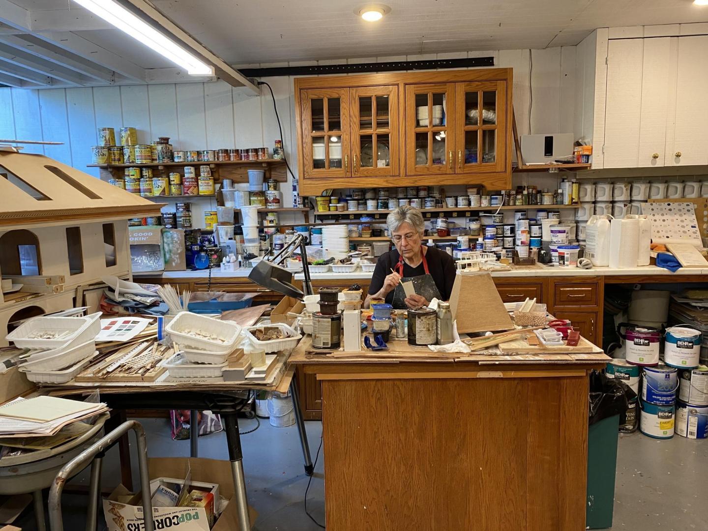 Sharon Ewert works on a detailed piece of a wooden dollhouse that she and her husband Norm are rebuilding in their basement workshop.