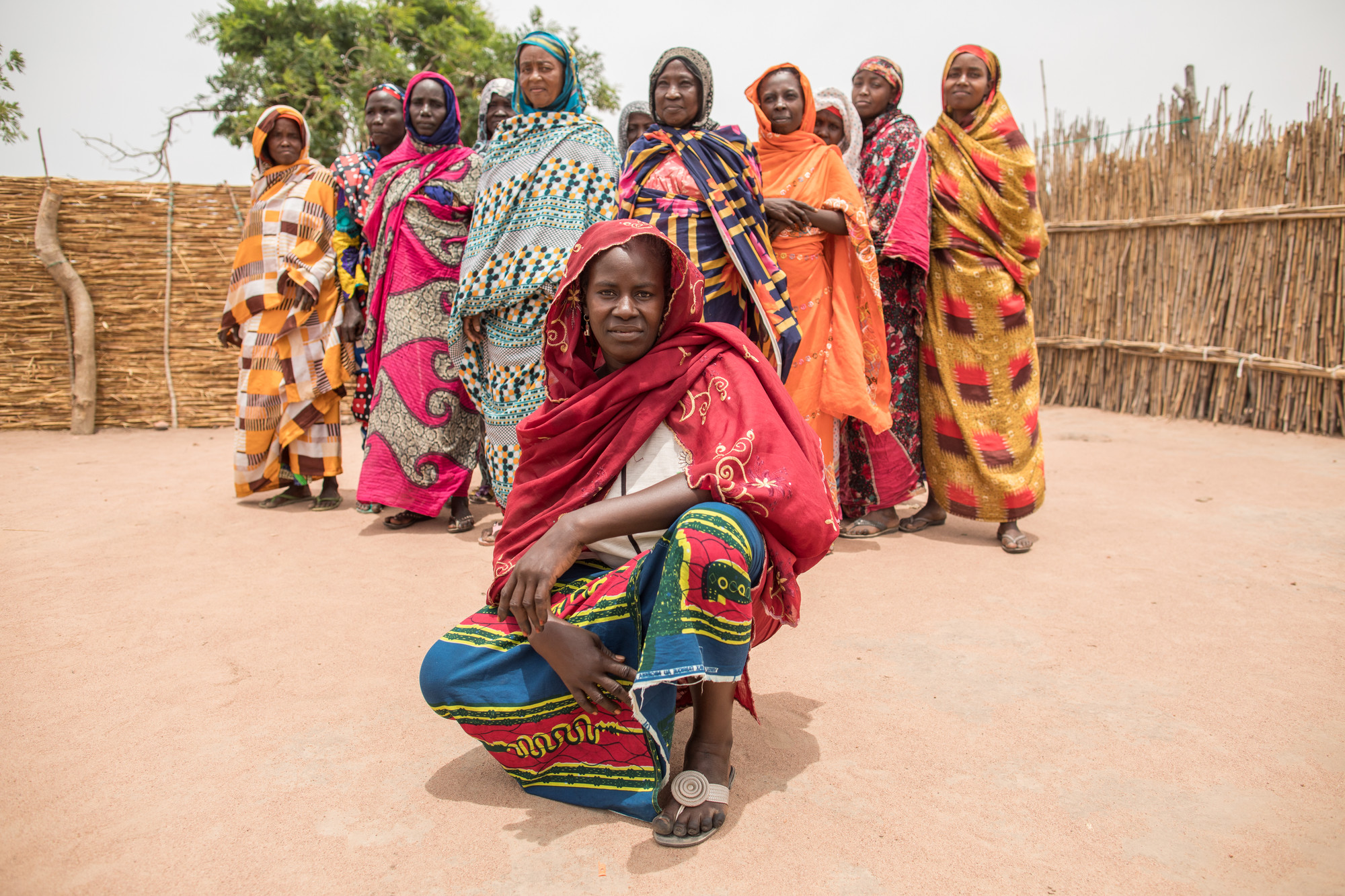 A Chadian woman squats in front of a group of women posing for the camera.