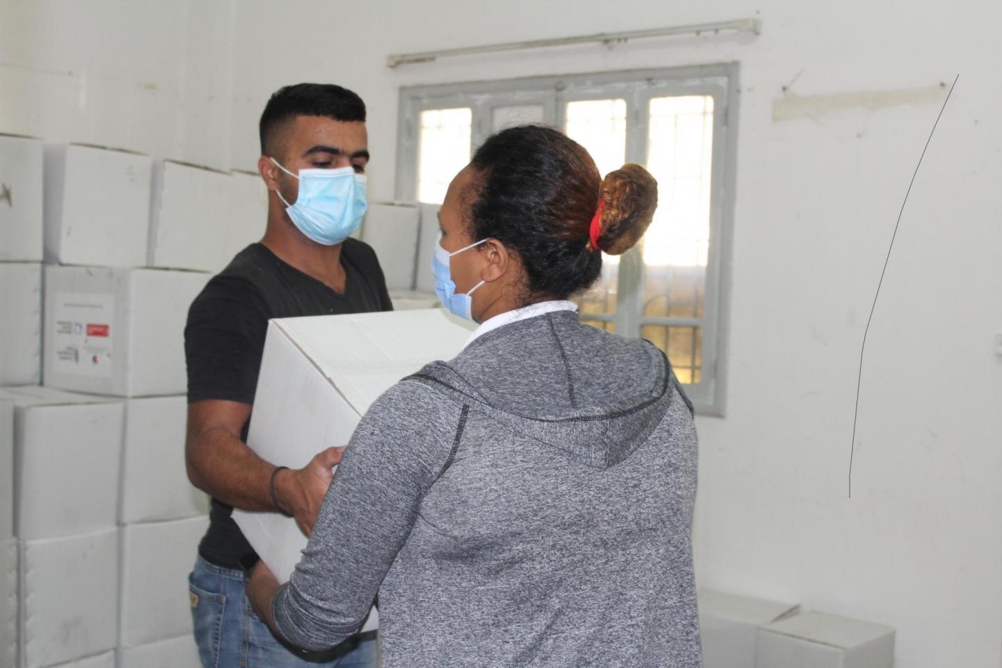 In November 2020, a staff person from The Popular Aid for Relief and Development (PARD), an MCC partner, hands a box of food to a woman who was impacted by the Beirut port explosion.