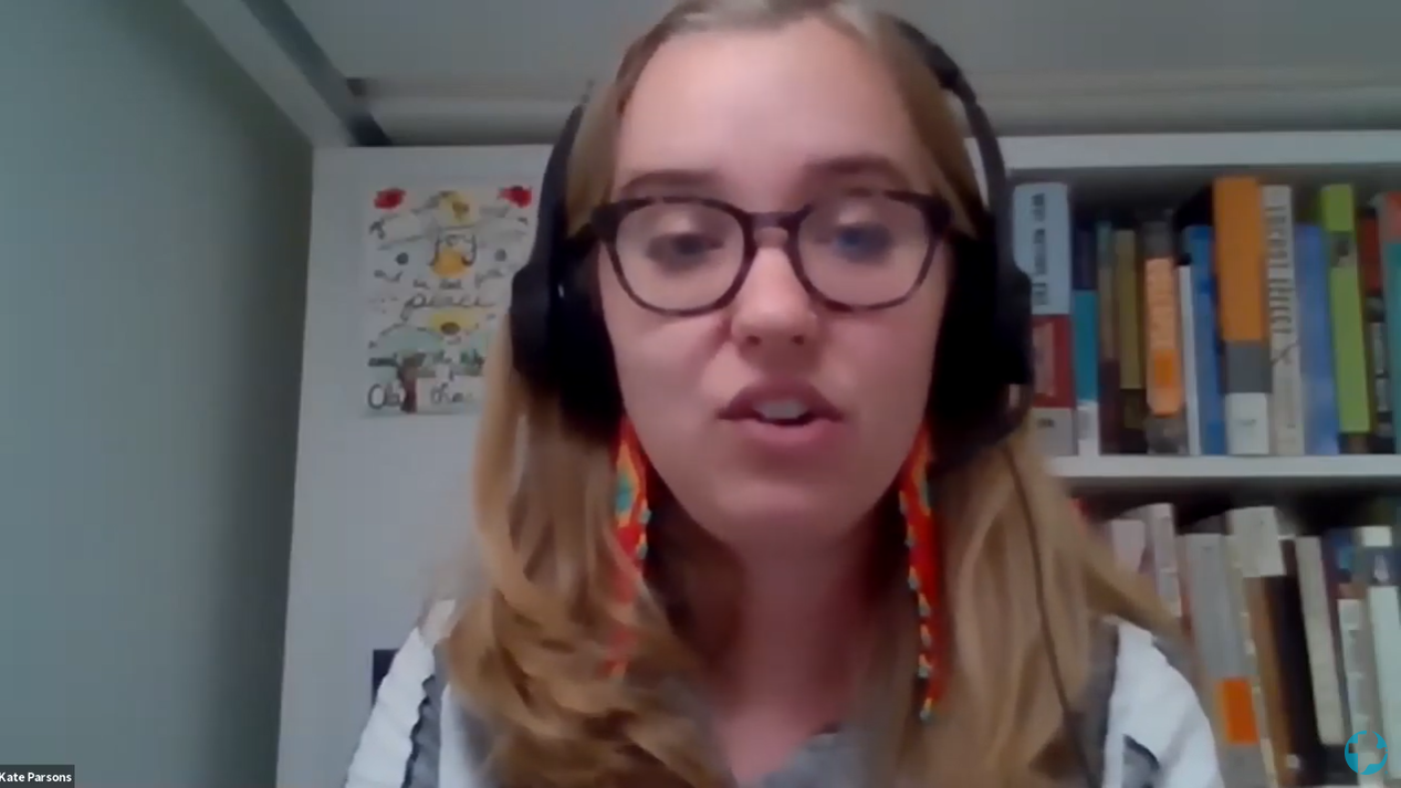 A young woman with glasses and headphones speaks into the camera during a webinar on zoom