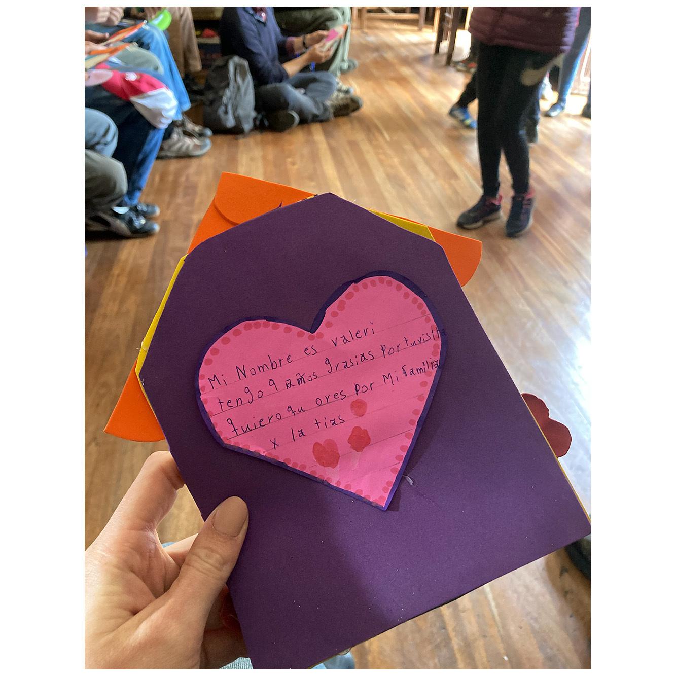 A homemade card with a pink heart and Spanish writing