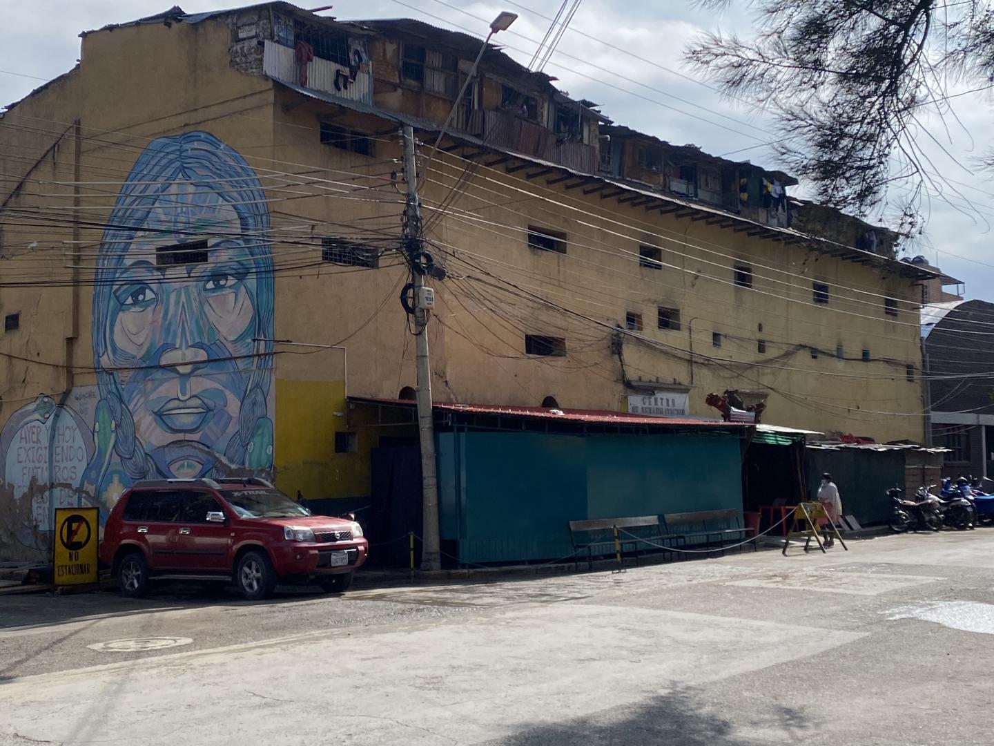 A prison building in Bolivia. There is a mural of a large face on the side of the building
