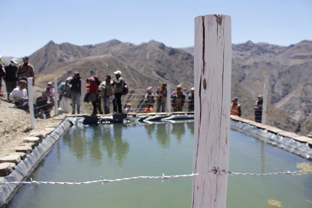 A group of people gather near a irrigation system pond