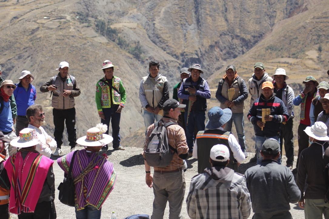 A large group of people stand in a circle on the side of a road in Bolivia
