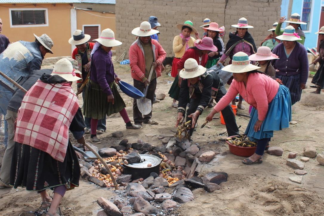 A group of Bolivians cook potatoes on an open fire pit