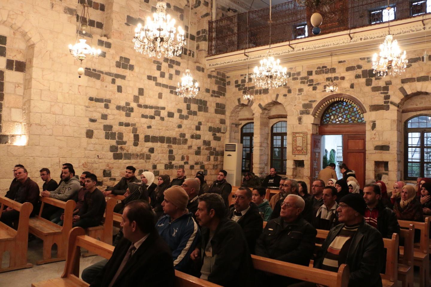People sitting in stone church sanctuary in Syria