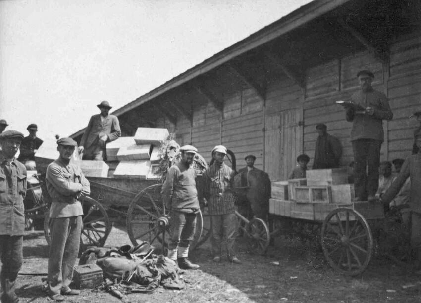A black and white photo from teh 1920s of men loading wagons