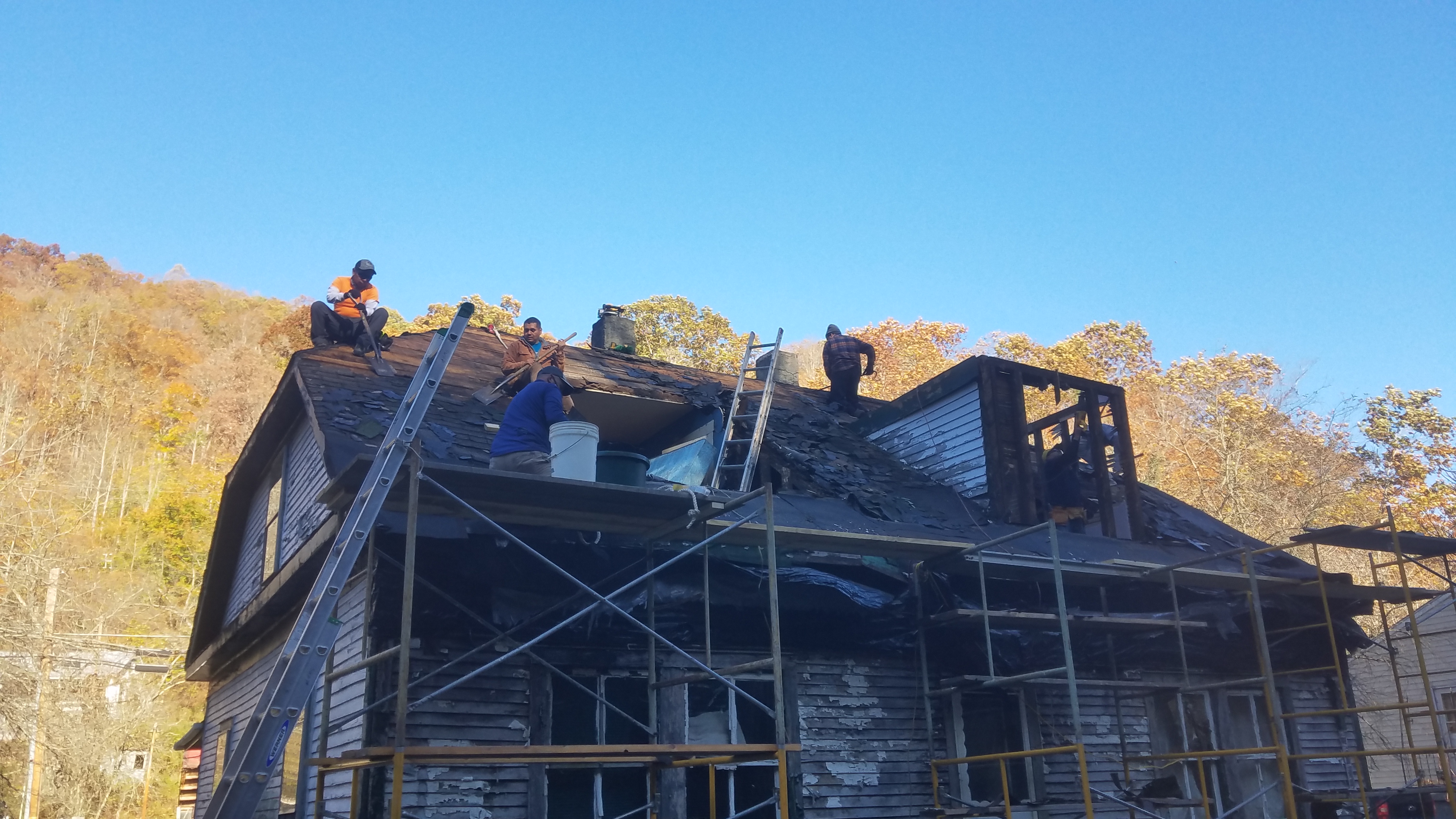 group of men on top of house roof repairing it