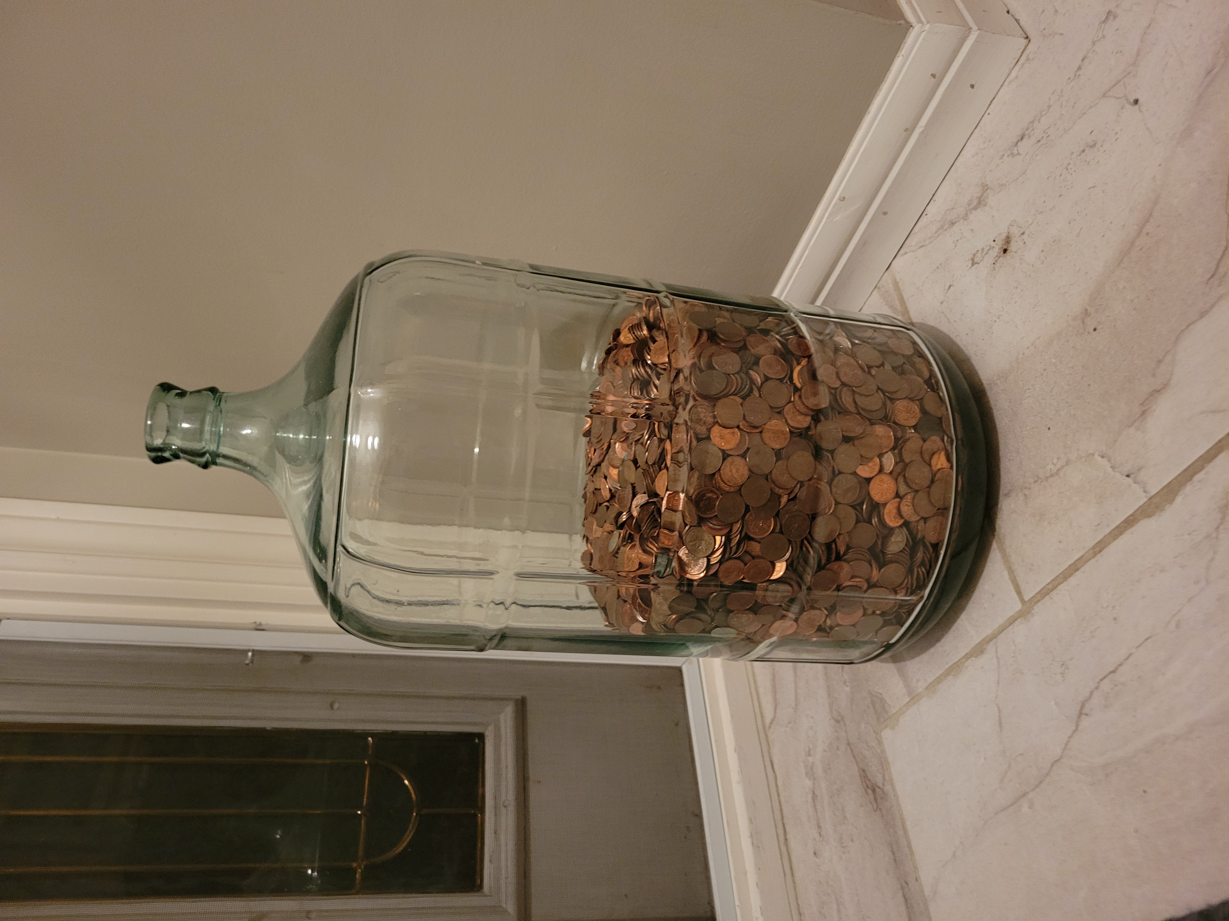 A glass jug half full of copper pennies.