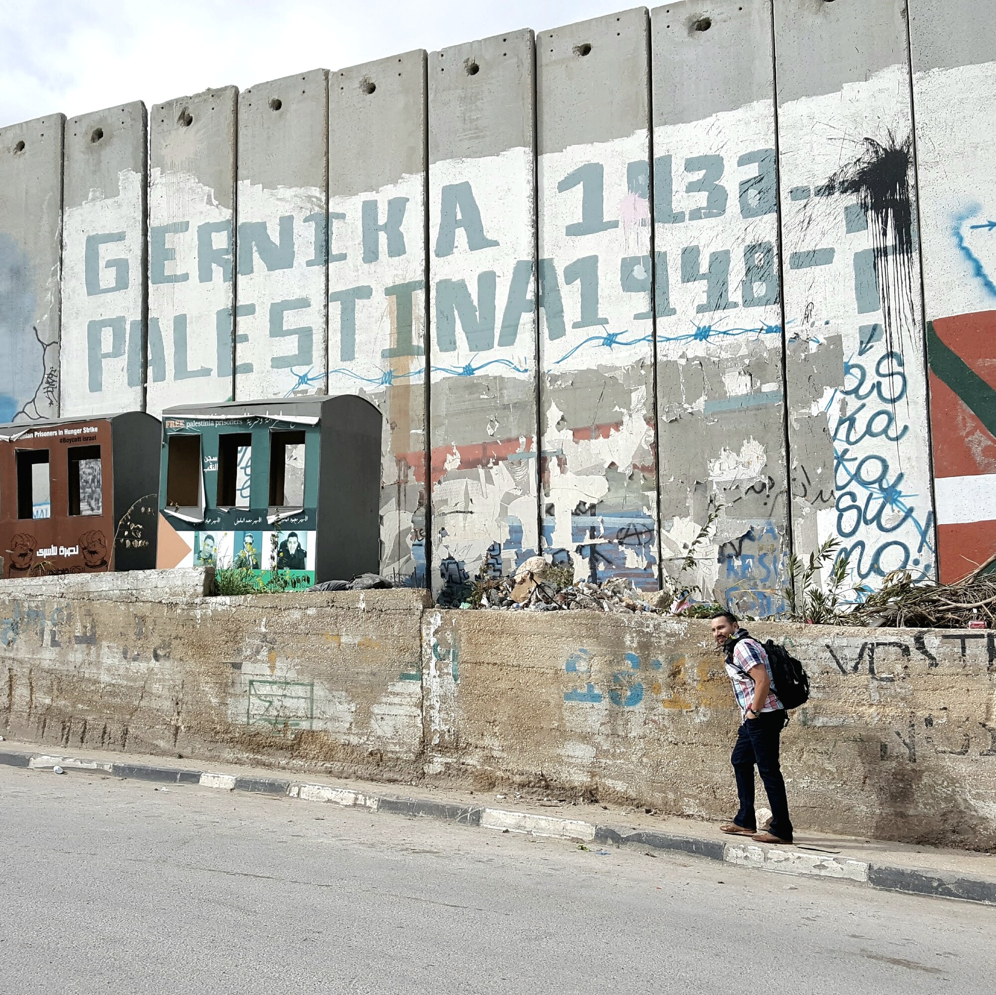Saulo Padilla standing in front of the Israel-Palestine border wall
