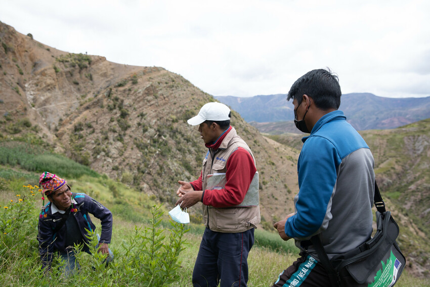 Gabriel Acarapi Chuca (middle) of MCC partner PRODII speaks with project participant Segundino Ignacio during a community visit with staff of MCC Bolivia and PRODII. Heraclio Mateo stands right.