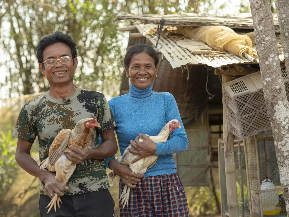A man and woman holding chickens