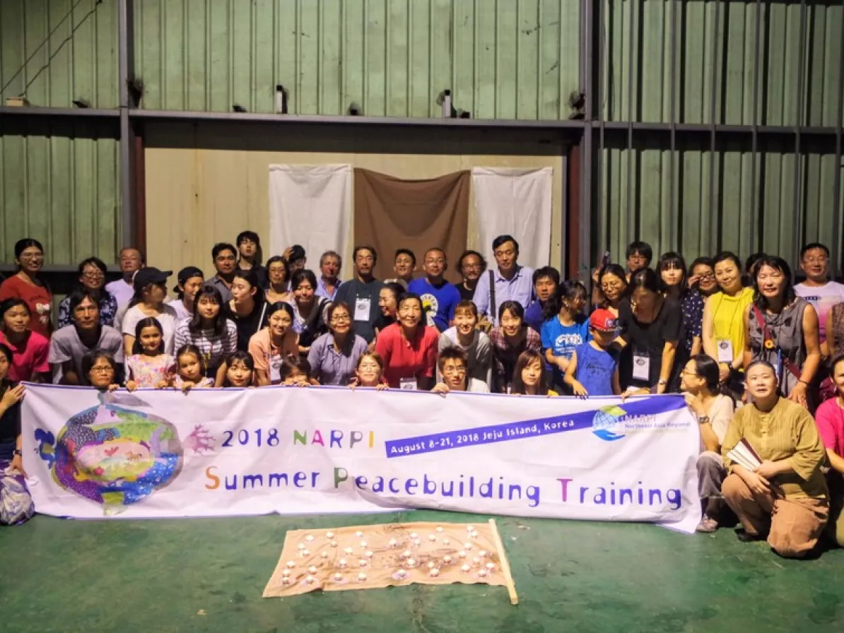 The group of participants in the August 2018 Northeast Asia Regional Peacebuilding Institute (NARPI), held in Republic of Korea (South Korea), hold the NARPI banner after a dramatic cultural performa