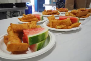 Multiple plates of watermelon and rollkuchen sitting on a table.