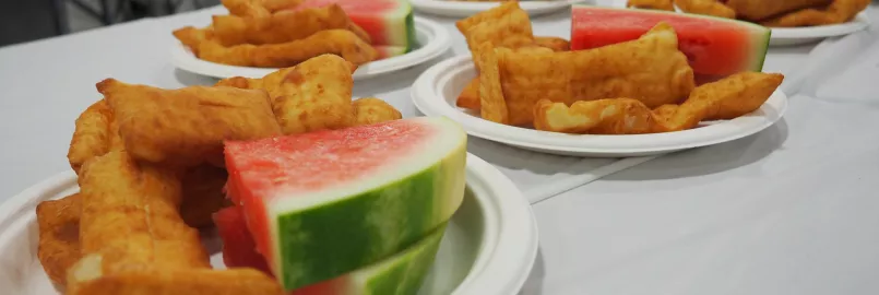Multiple plates of watermelon and rollkuchen sitting on a table.