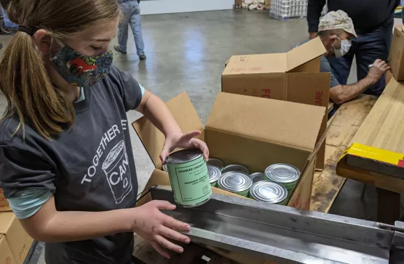 Young girl boxing canned goods
