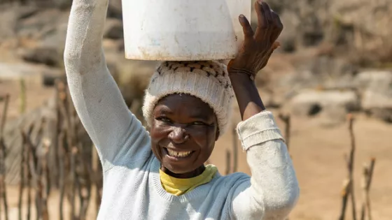 Rebecca Murereki holds an empty pail on her head that she uses to carry cow dung to her biodigester.