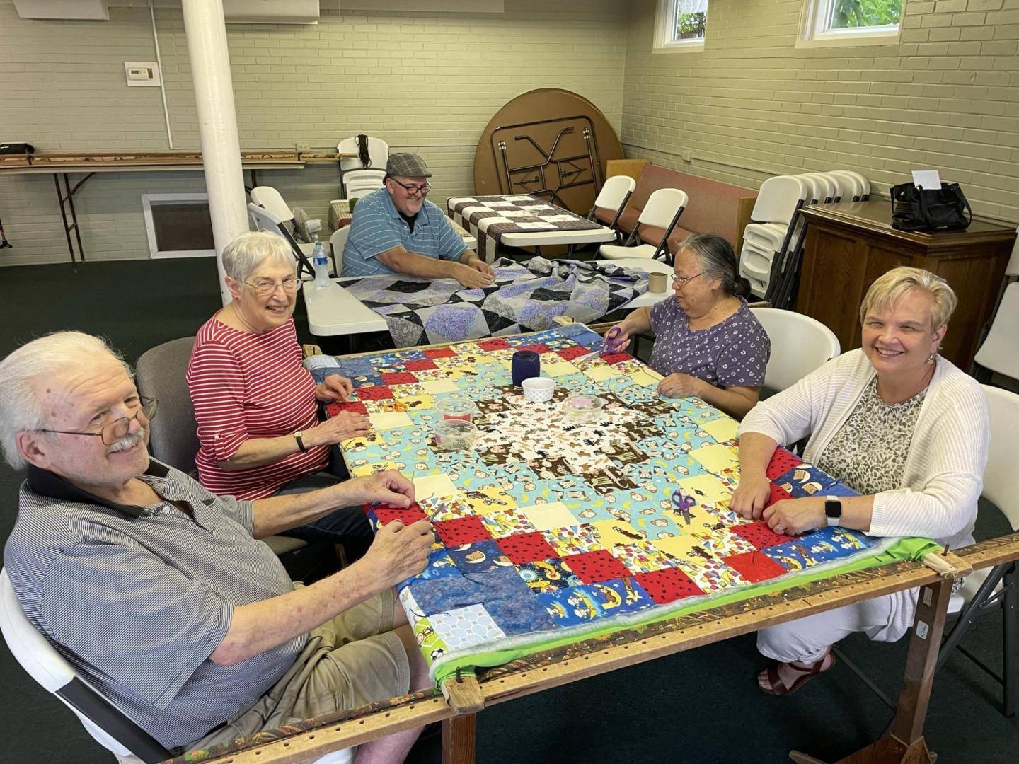 A group of five people sewing comforters
