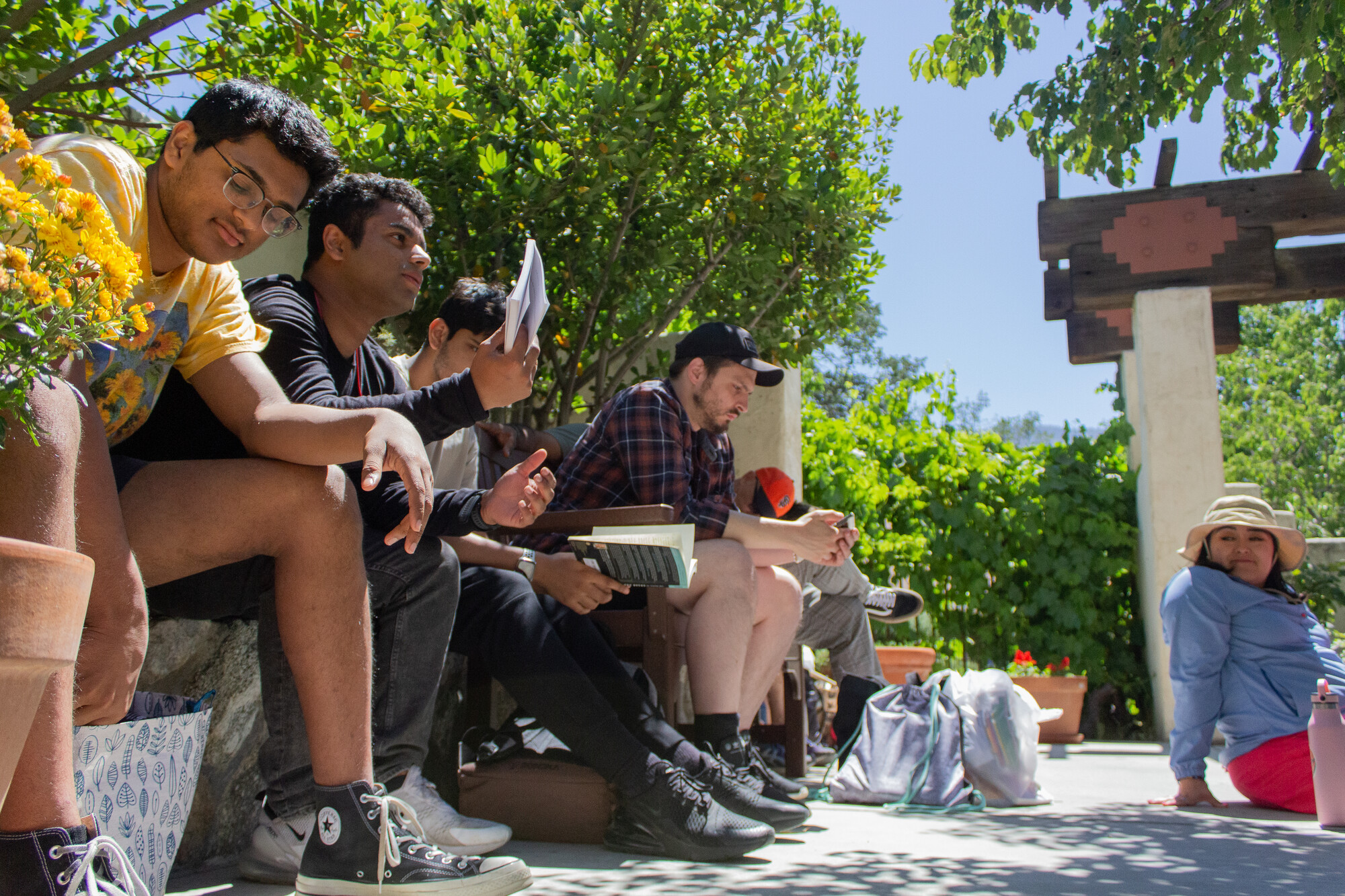 A group of young adults sits in a row outside