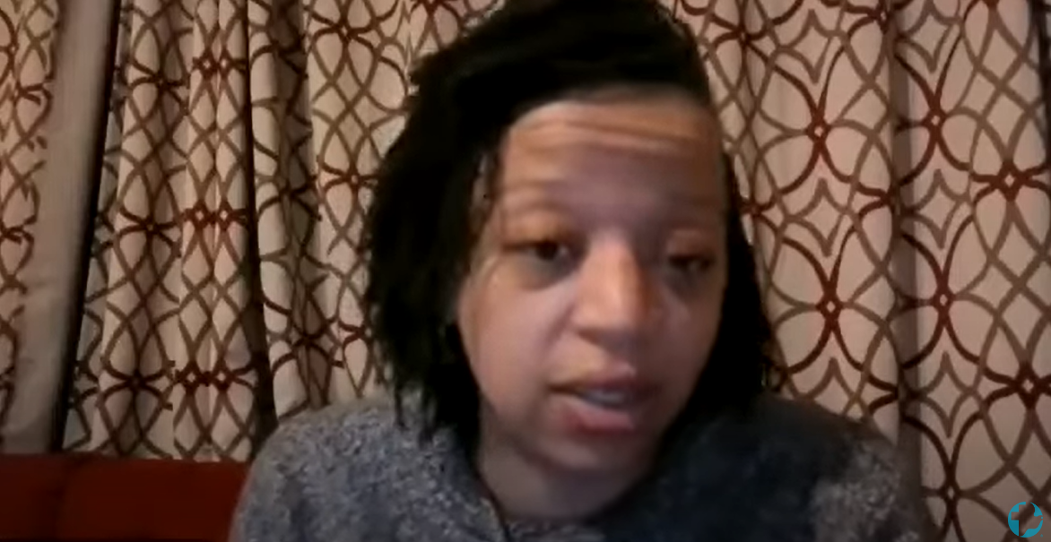 A woman with short dreads speaks into the camera during a video call