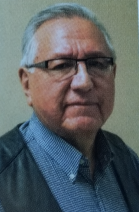 A portrait of an older man with grey hair and glasses