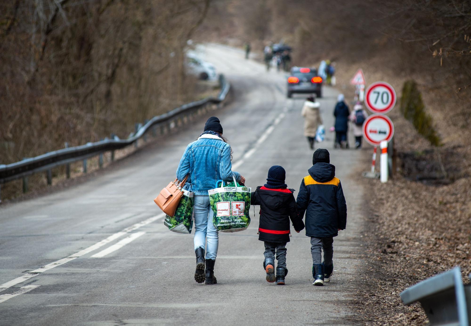 A woman and two children walk down a road.