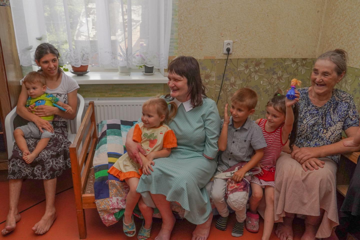 A group of three Ukrainian women and three children sit together.