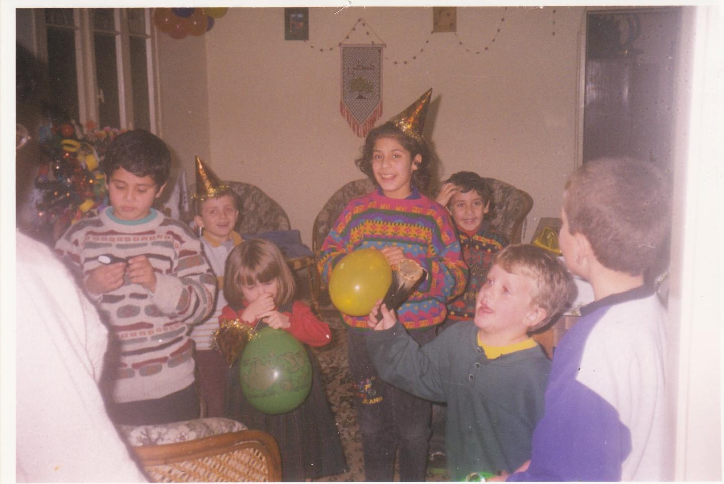 A group of children in a living room with balloons