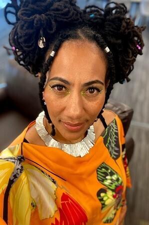 A woman with her hair in two buns and a brightly colored orange shirt