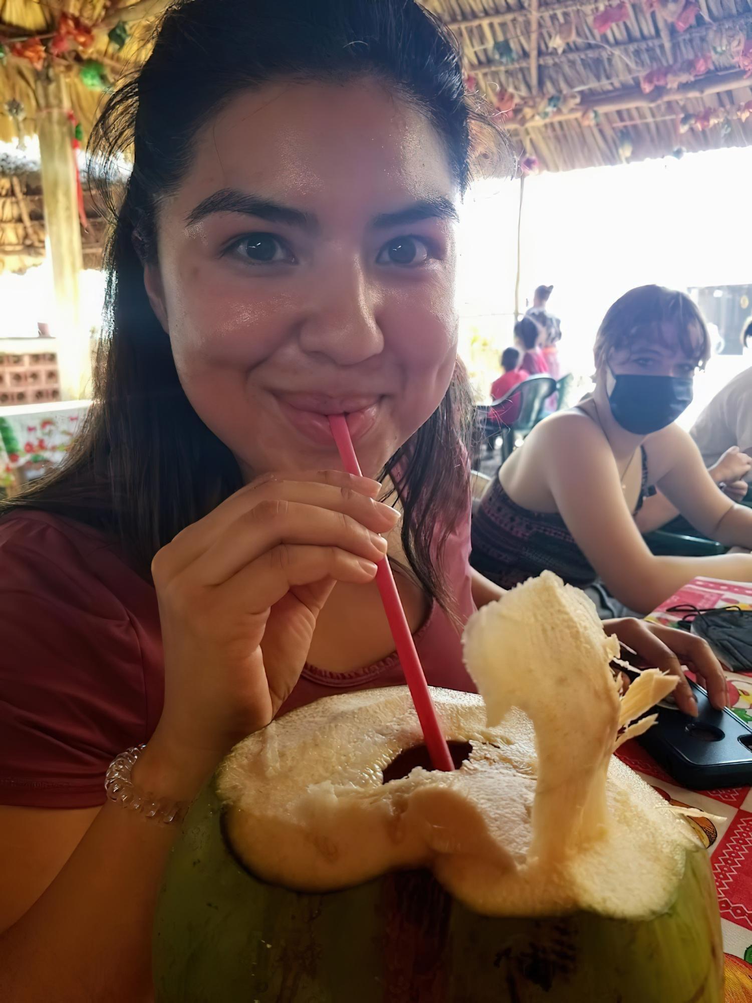 A young latinx woman drinking from a coconut