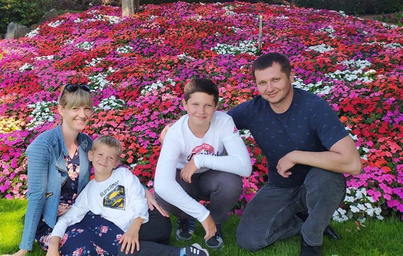 A woman and man sitting near flowers with two young boys