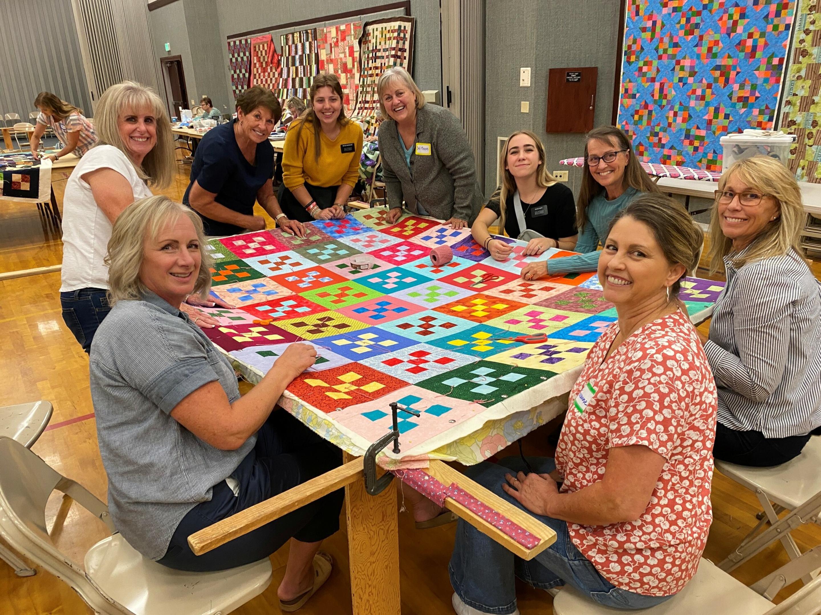 A group of people sewing a comforter together