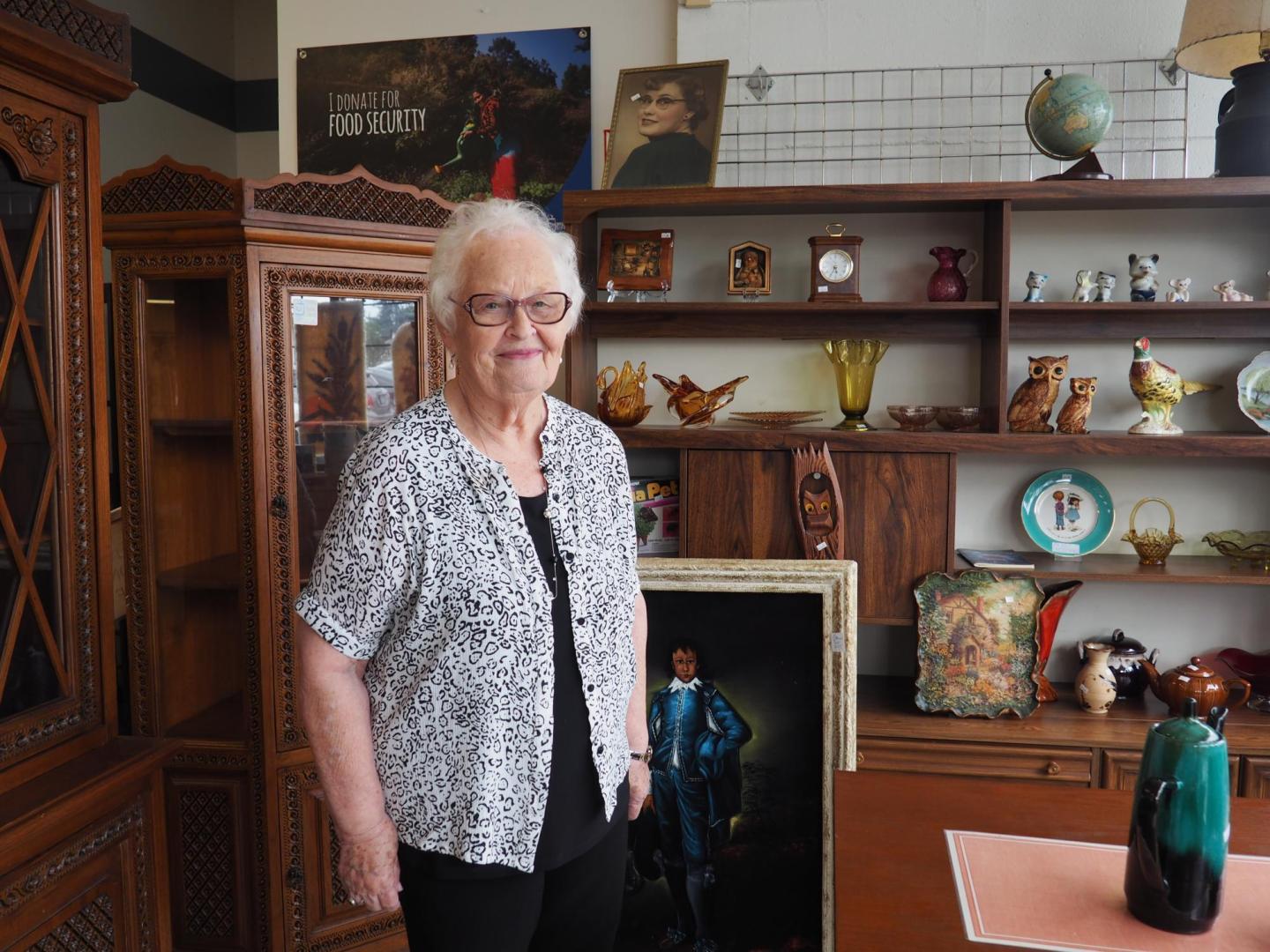 Woman standing in front of a cabinet with knickknacks.
