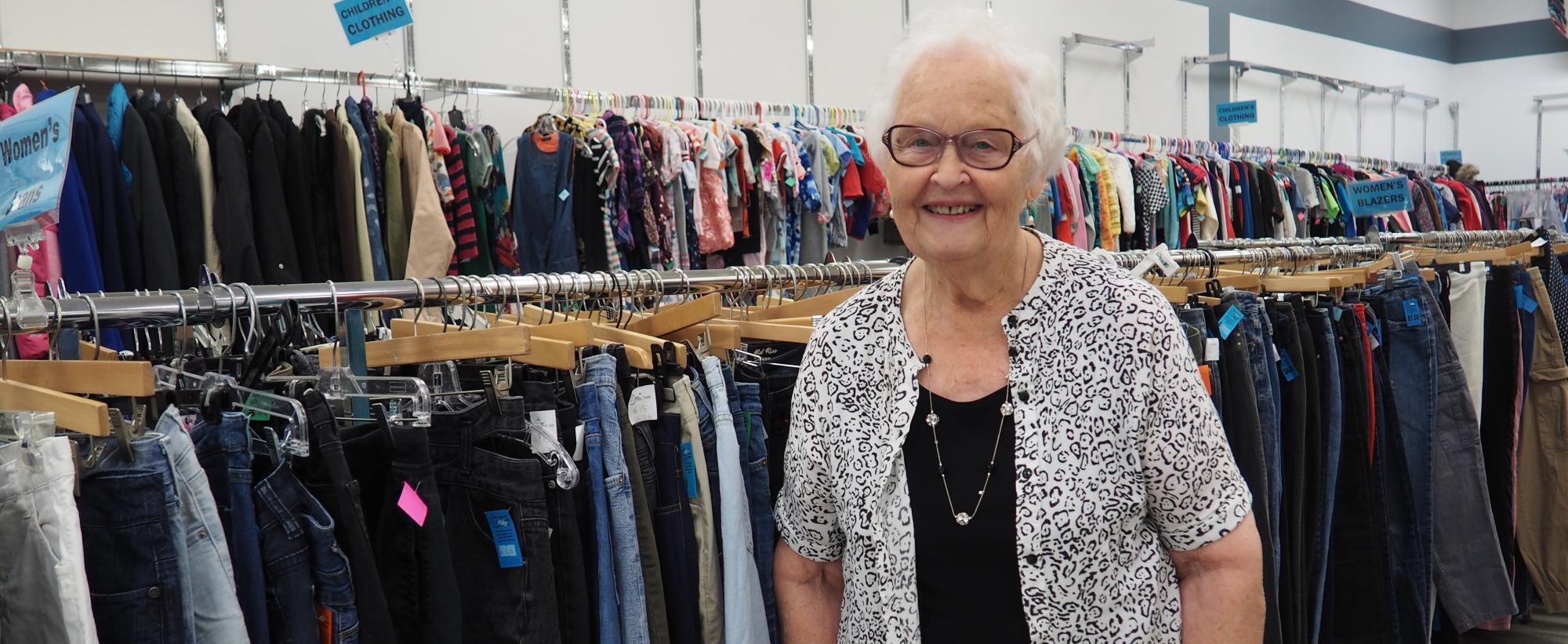 Woman standing in front of two racks of clothing.