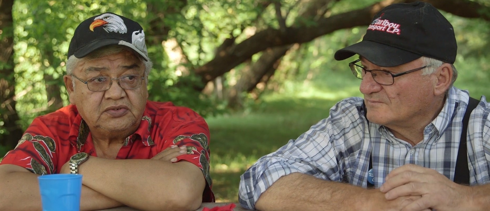 Two Indigenous Elders sit and talk with one another.