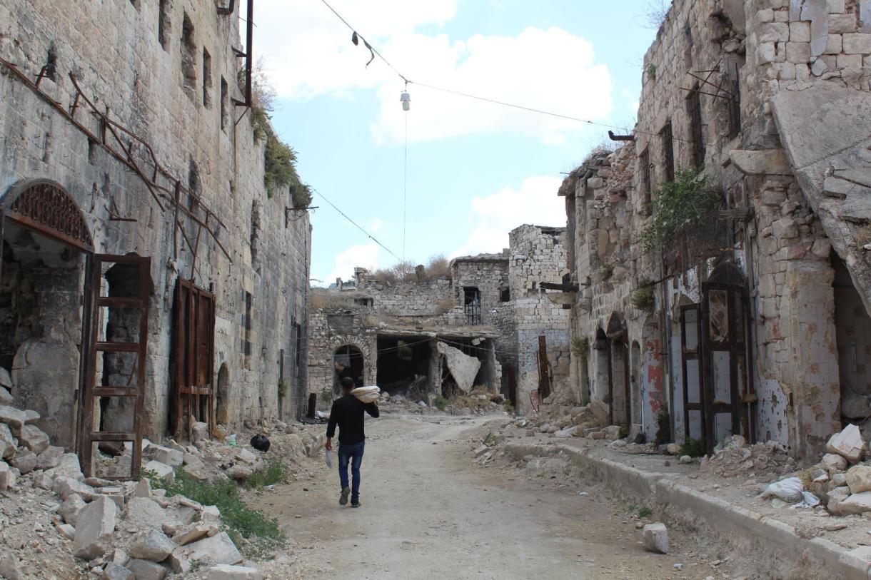 A man walking between two ruined buildings