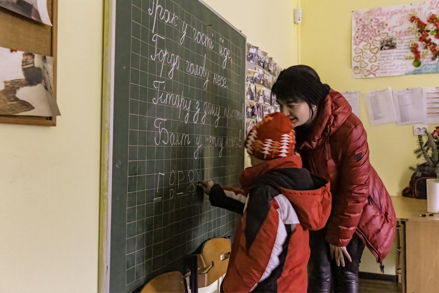 A woman teaching a child in a classroom