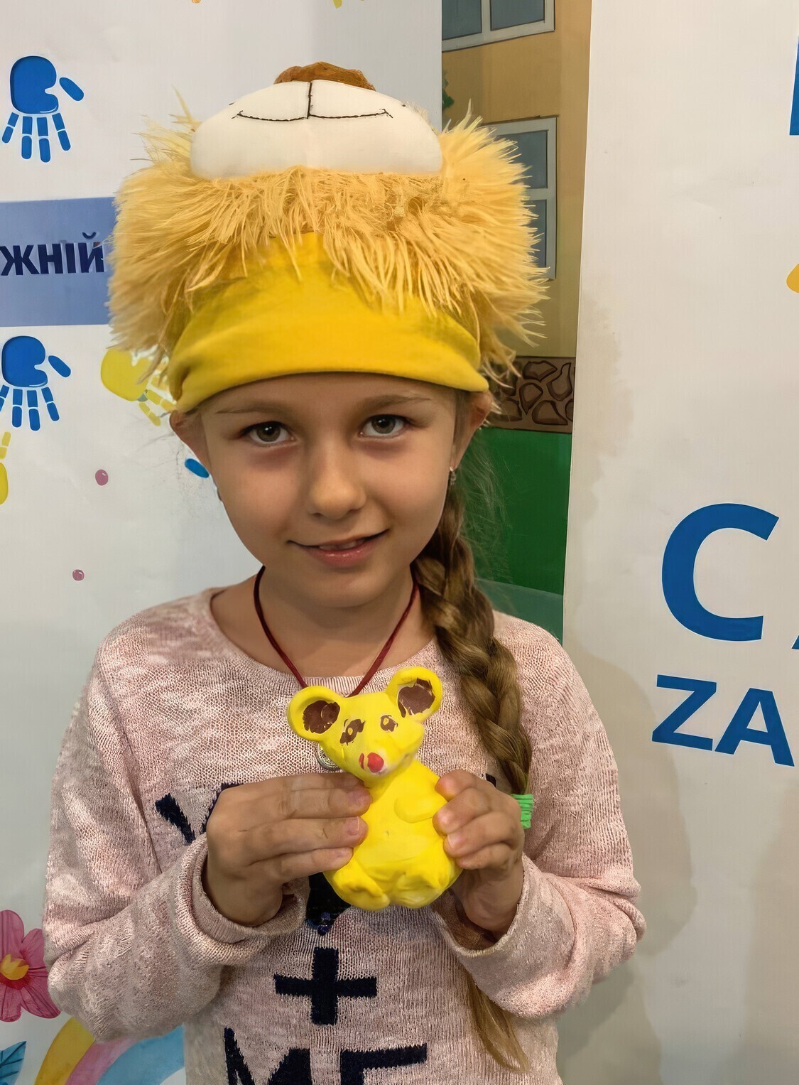 A young girl holding an animal made of clay