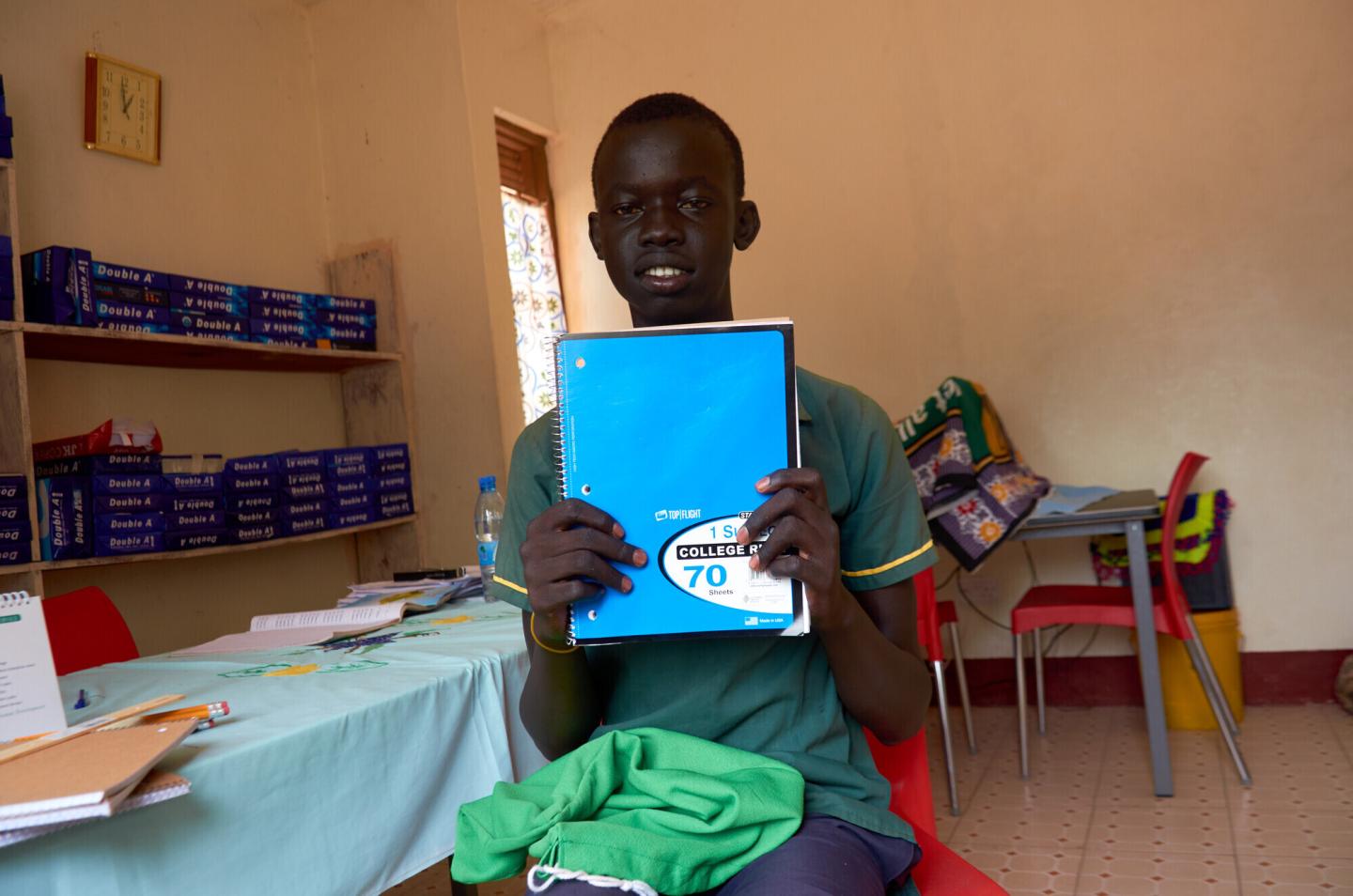 A student holds up the notebook he received from a school kit