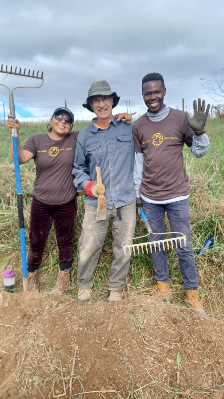 Three people standing for a photo on a farm