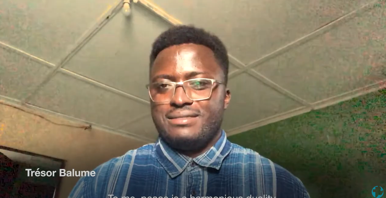 A young Zambian man in a blue plaid shirt with glasses.