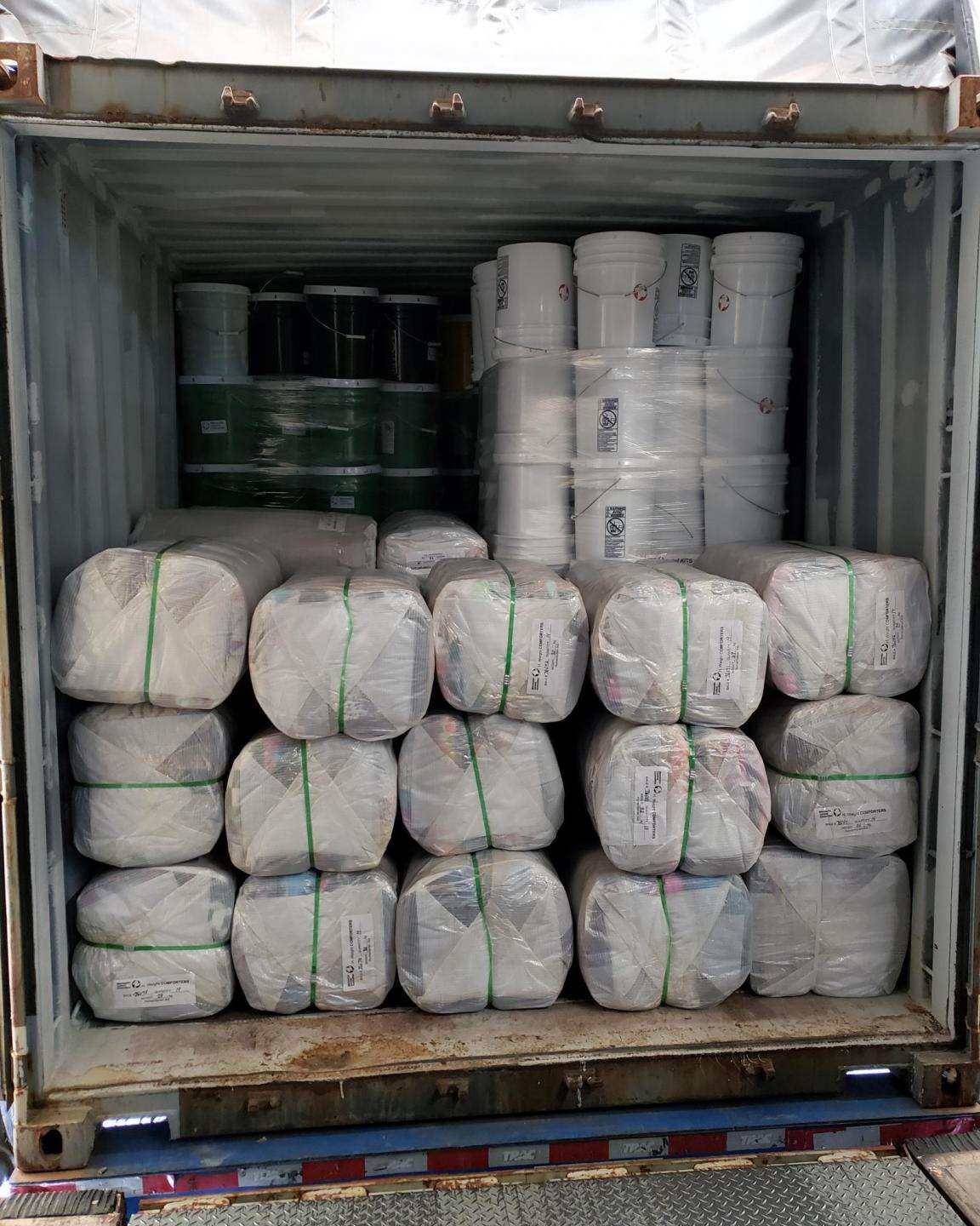 A shipping container filled with white plastic bales and buckets.
