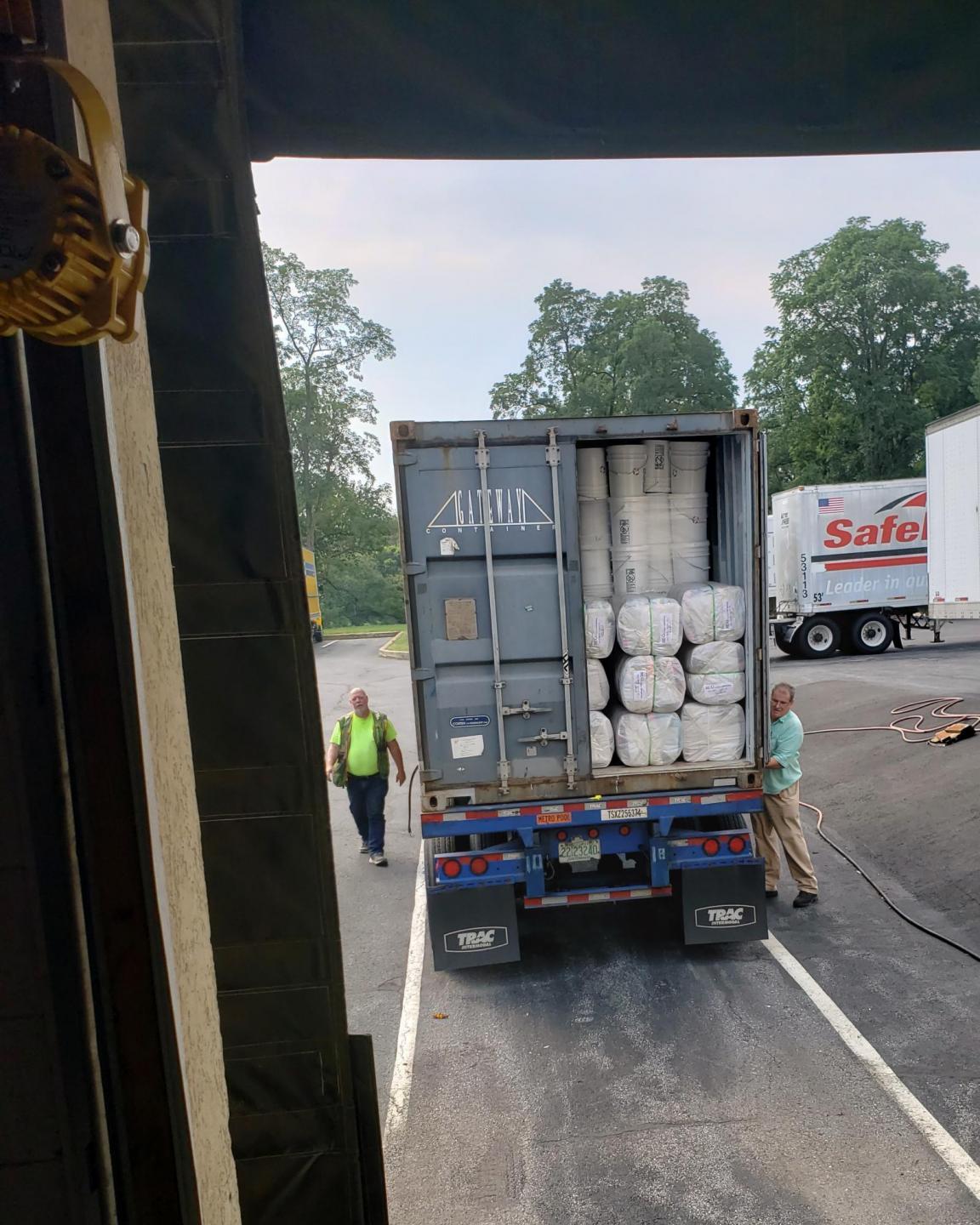 Two men work on closing the trailer doors on a semi truck