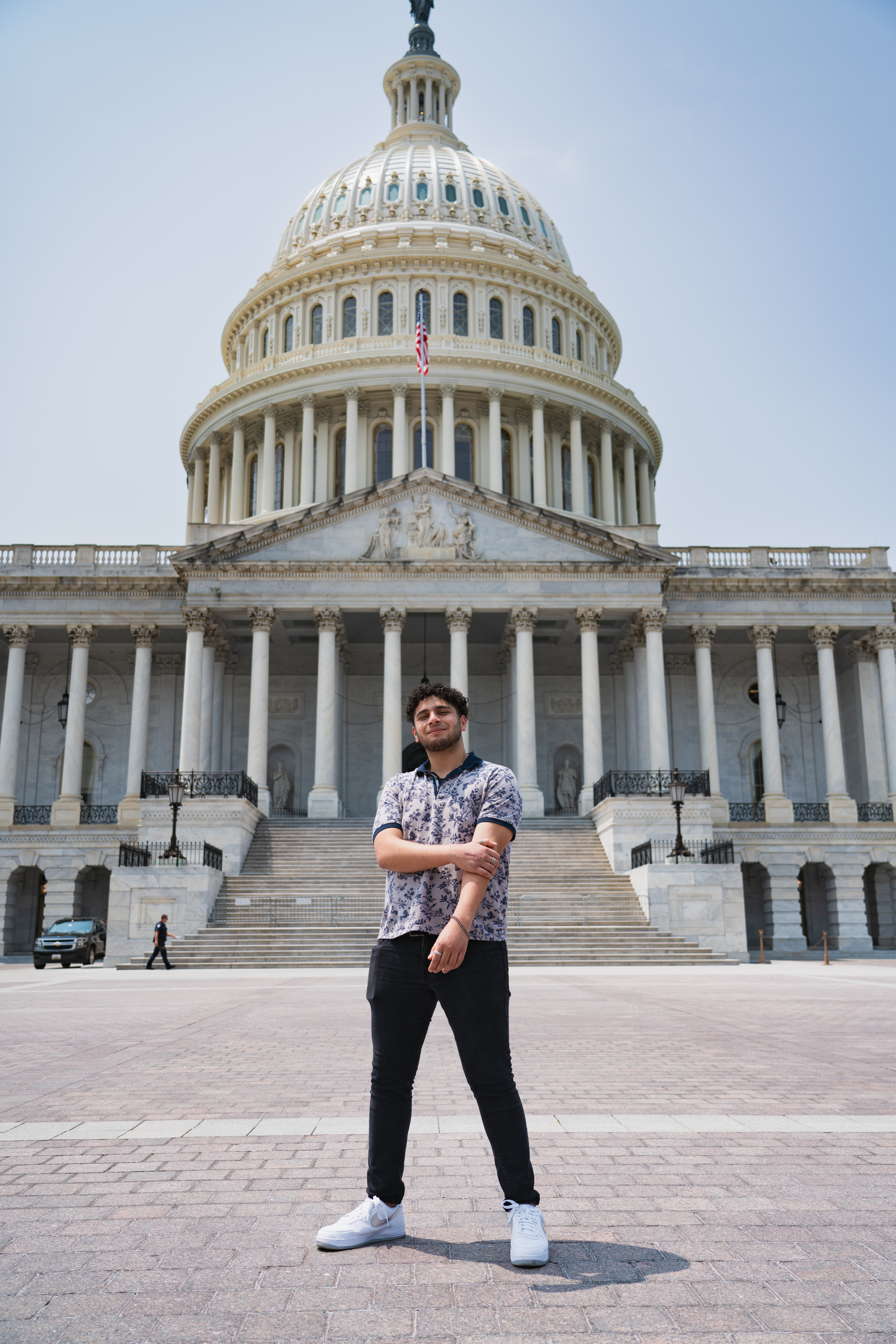 A young adult stands in front of the U.S. capital building