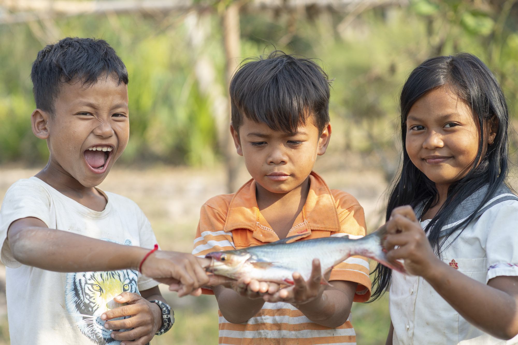 Three children holding a fish