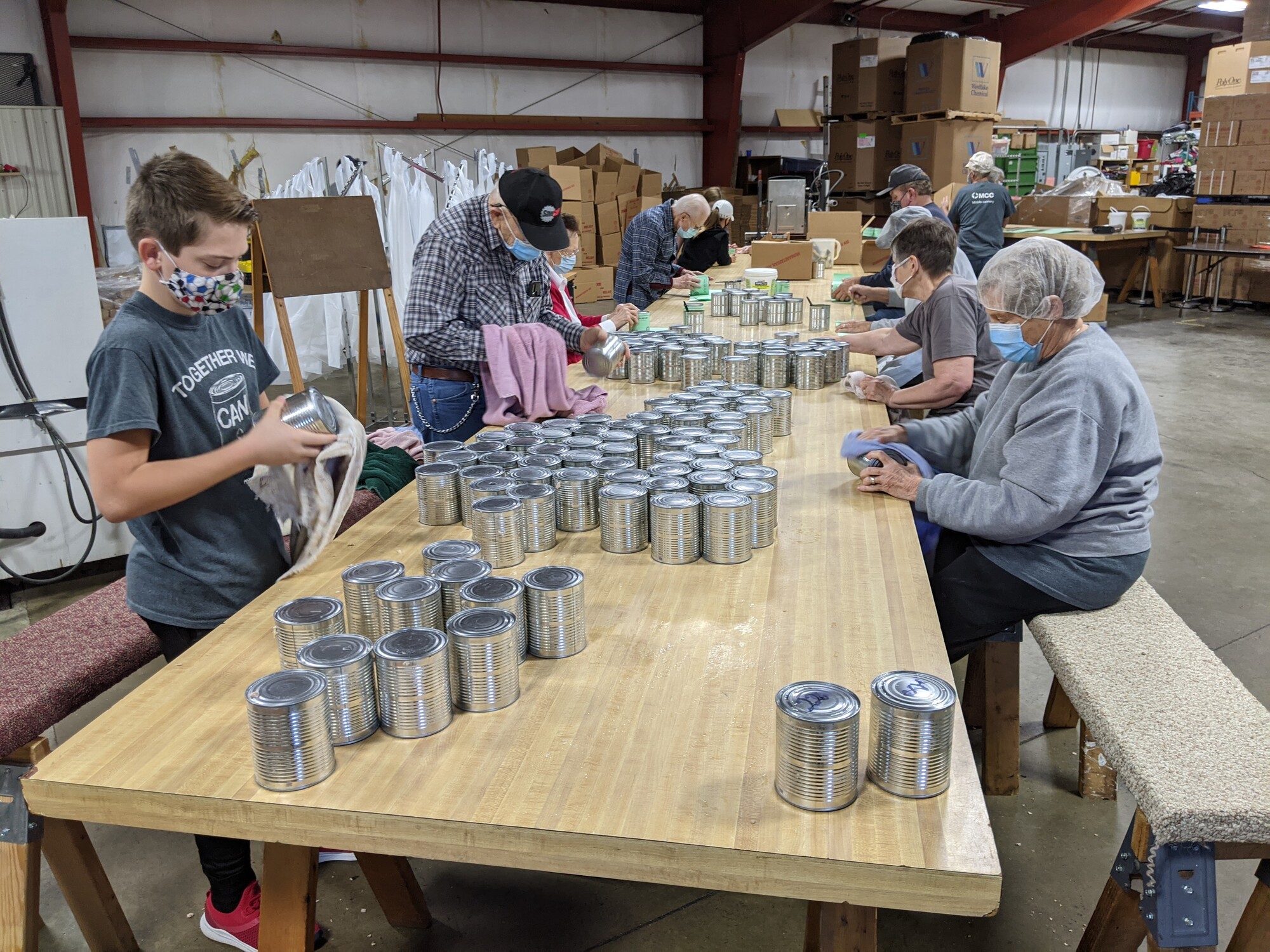 Group of volunteers putting labels on cans.