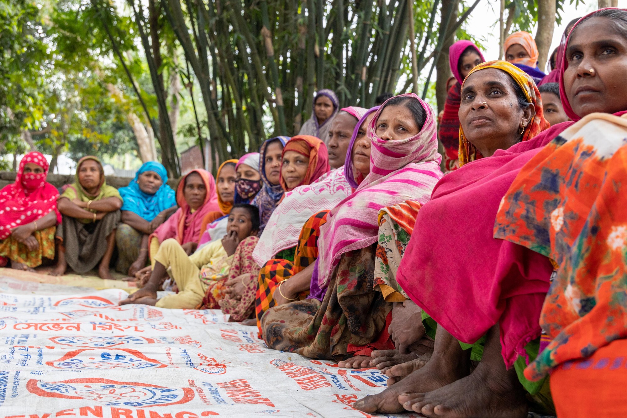 A group of Bangladeshi women sit on a mat outside