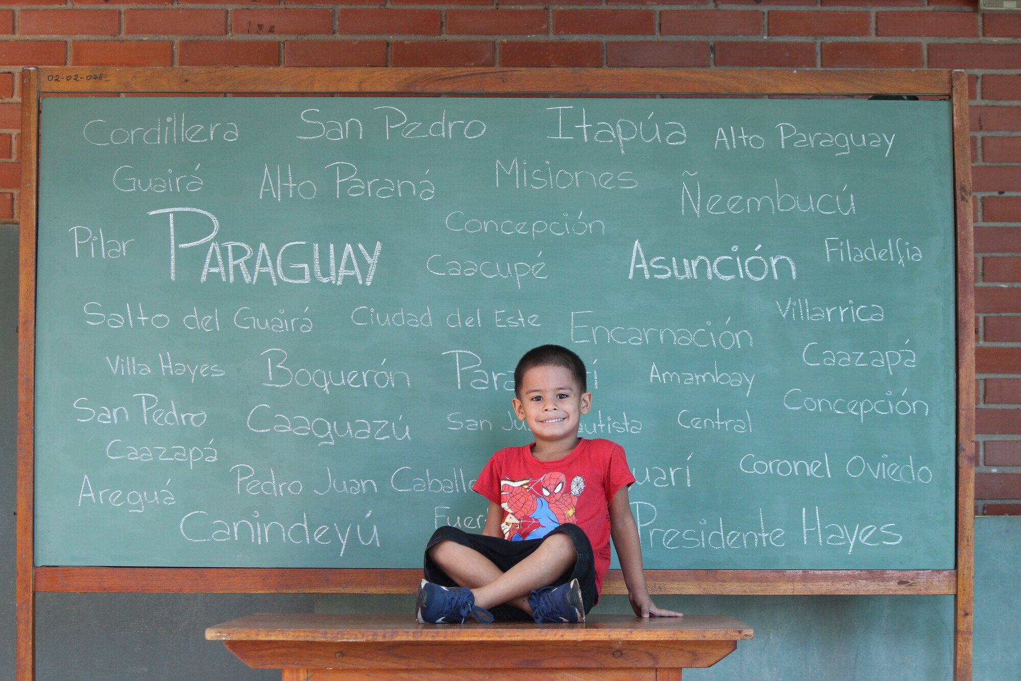 A boy sits in front of a chalkboard